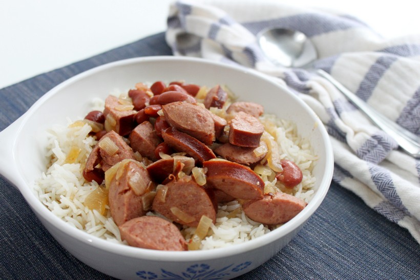 Bowl of red beans and rice on blue place mat with striped towel and spoon