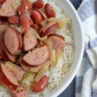 Bowl of red beans and rice on blue place mat with striped towel and spoon close up