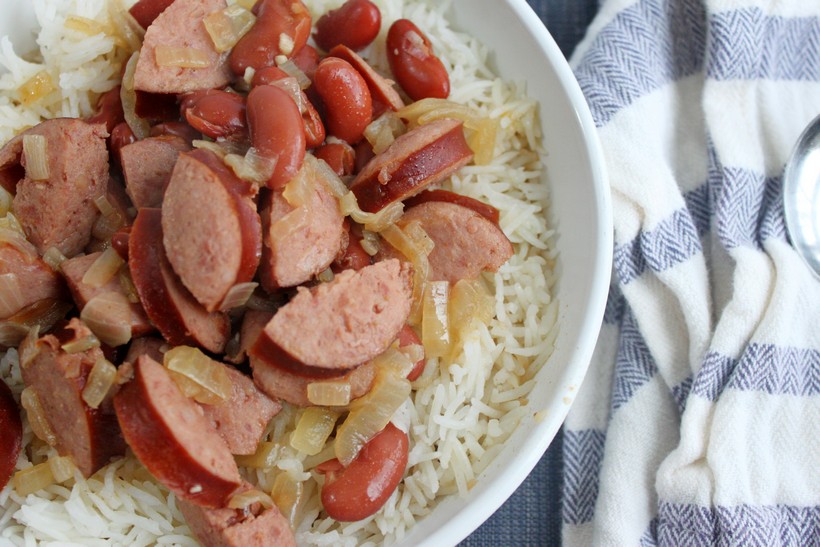 Bowl of red beans and rice on blue place mat with striped towel and spoon close up
