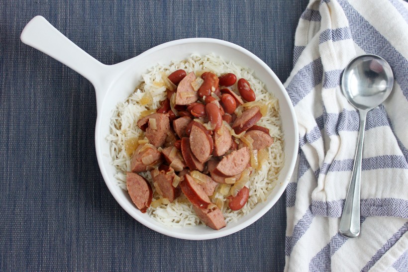 overhead shot of bowl of red beans and rice on blue place mat with striped towel and spoon