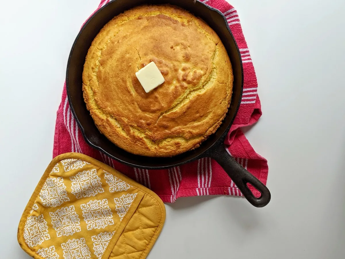 Cornbread in cast iron skillet with butter and pot holder