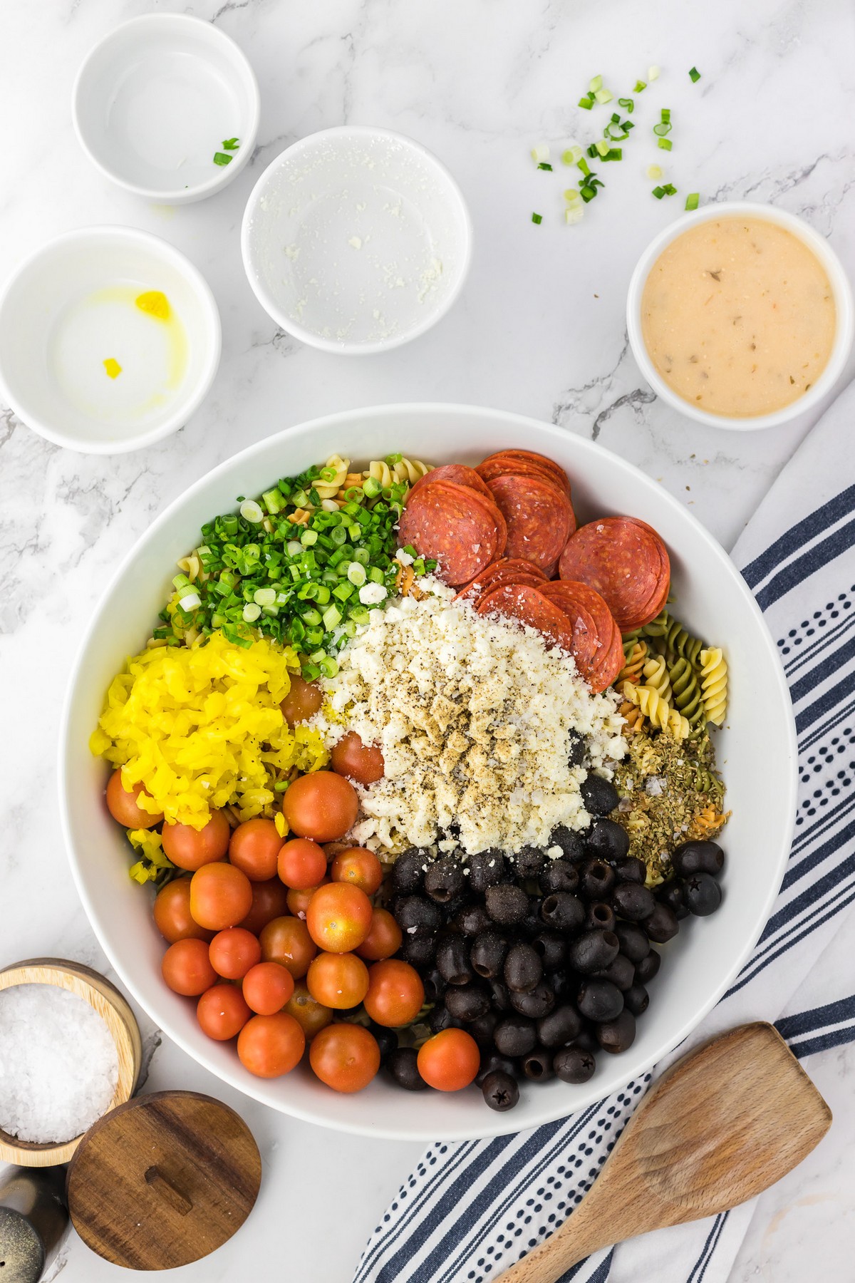 adding pasta salad ingredients to mixing bowl