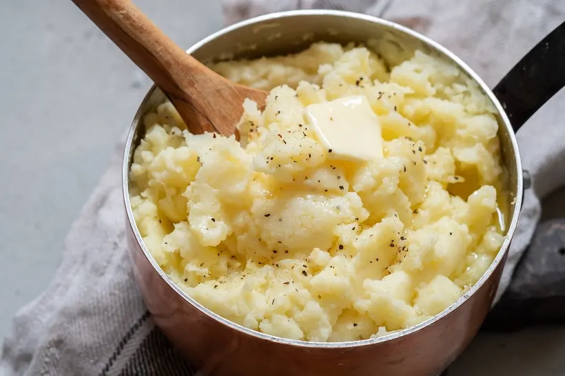 Mashed potato with spoon, in a copper pot