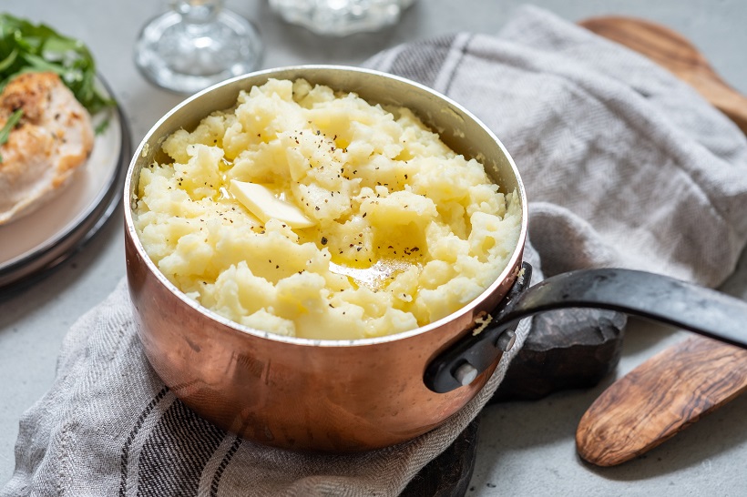 Mashed potato with spoon, in a copper pot