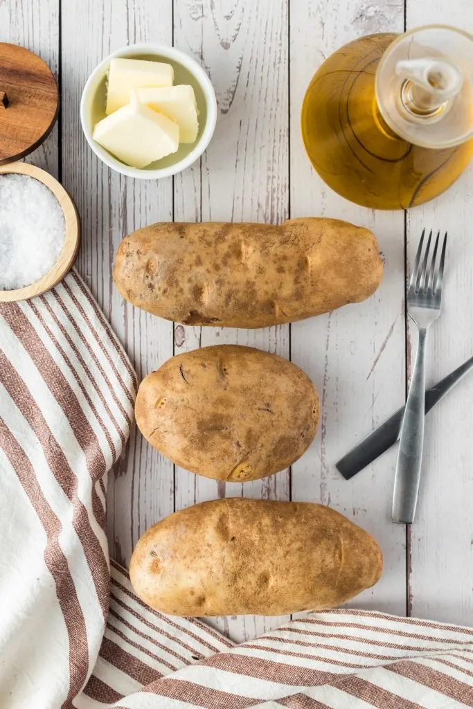 potatoes, olive oil, butter, salt, and utensils on a white background