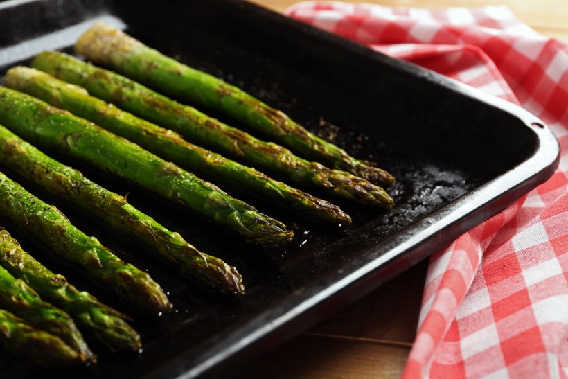Roasted asparagus on pan, close-up, on table background
