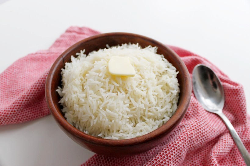 White rice in wooden bowl with butter spoon and red towel