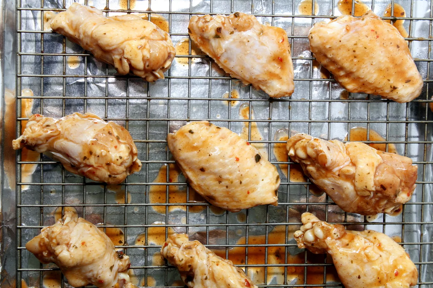 These chicken wings are tender on the inside and covered with perfectly sticky BBQ sauce on the outside. Nothing quite says gameday like these oven-baked wings! #wings #chickenwings #bakedwings #bakedchickenwings #recipe #easyrecipe #appetizers #appetizerrecipes #appetizerseasy #appetizersforparty #gamedayrecipes #gamedayfood Chicken wings on baking sheet with foil