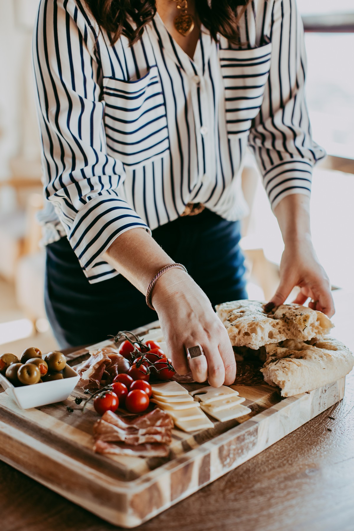 assembling bread on cutting board with meats and cheeses