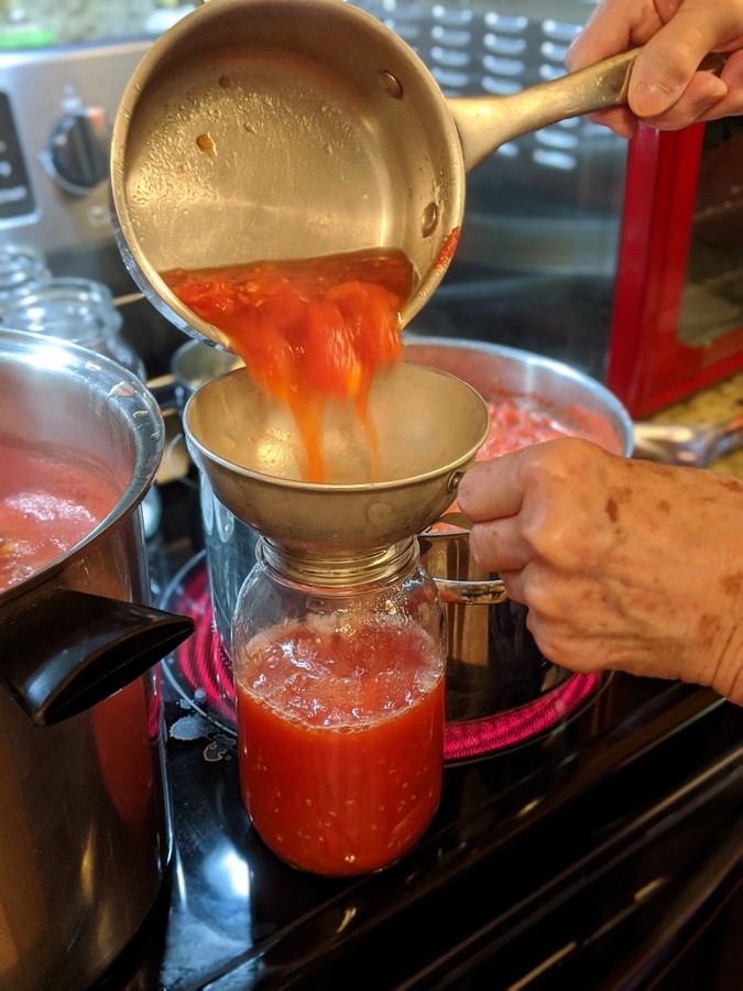 Funneling tomatoes into jars