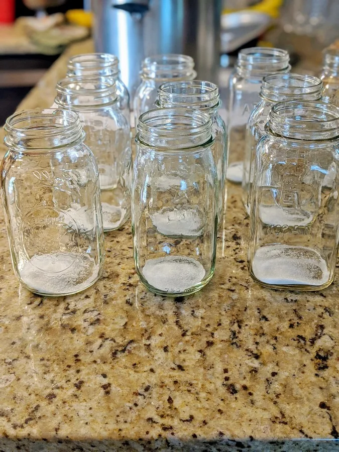 Empty mason jars for canning with salt and sugar in the bottom