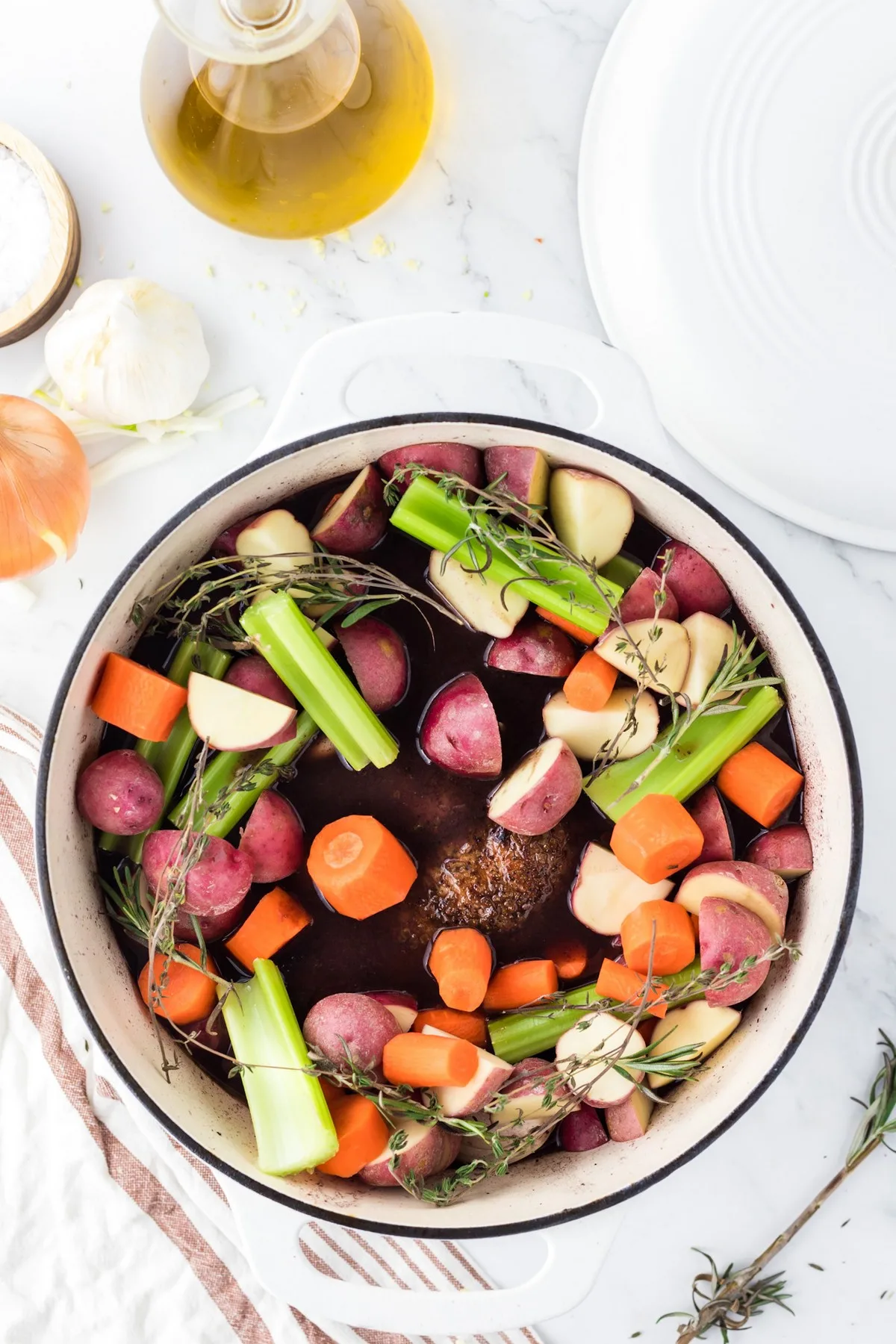 adding vegetables to dutch oven with meat