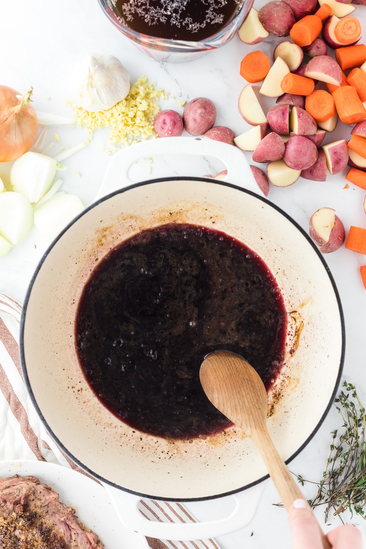 dutch oven with red wine inside and wooden spoon, deglazing pan