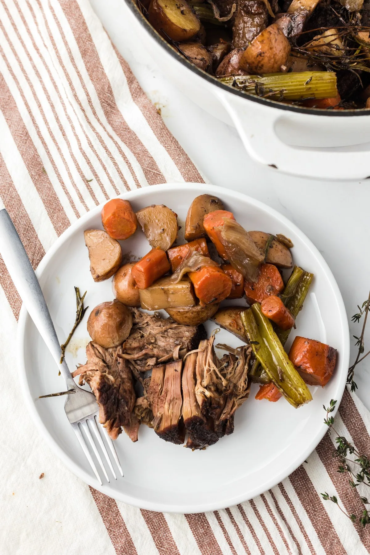 overhead shot of shredded pot roast with vegetables on white plate