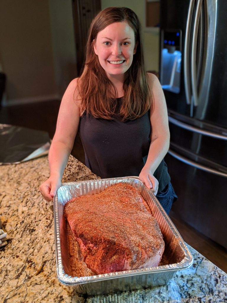 Female with large beef brisket in pan