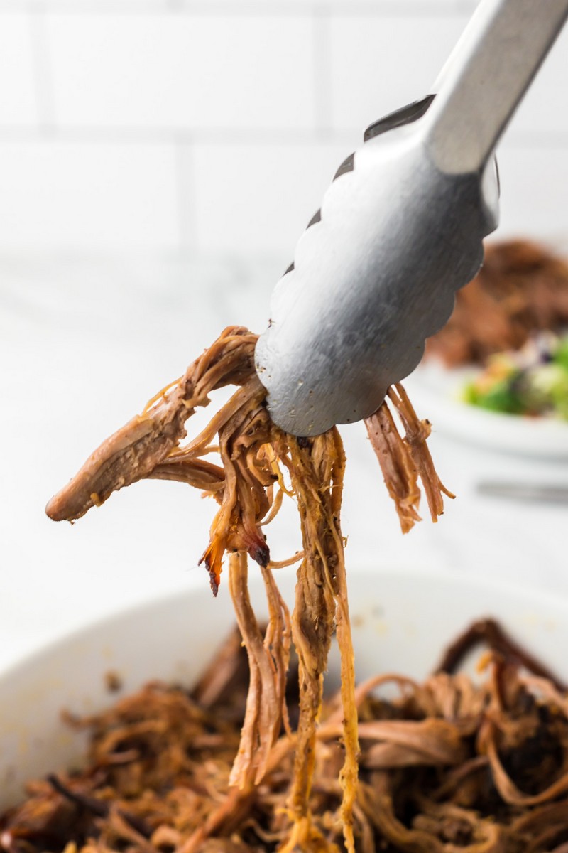 up close shredded brisket in tongs