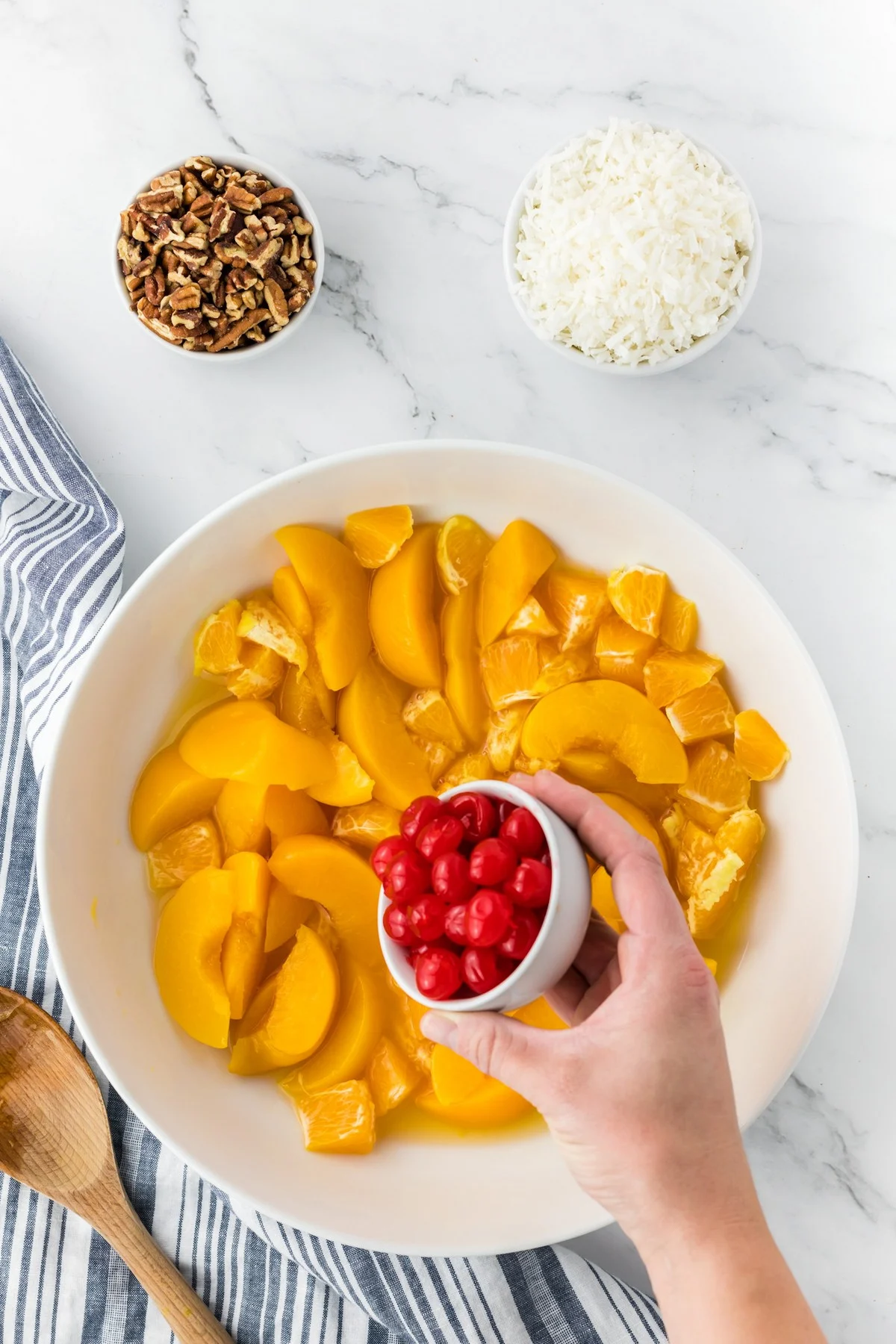 adding cherries to ambrosia fruit salad