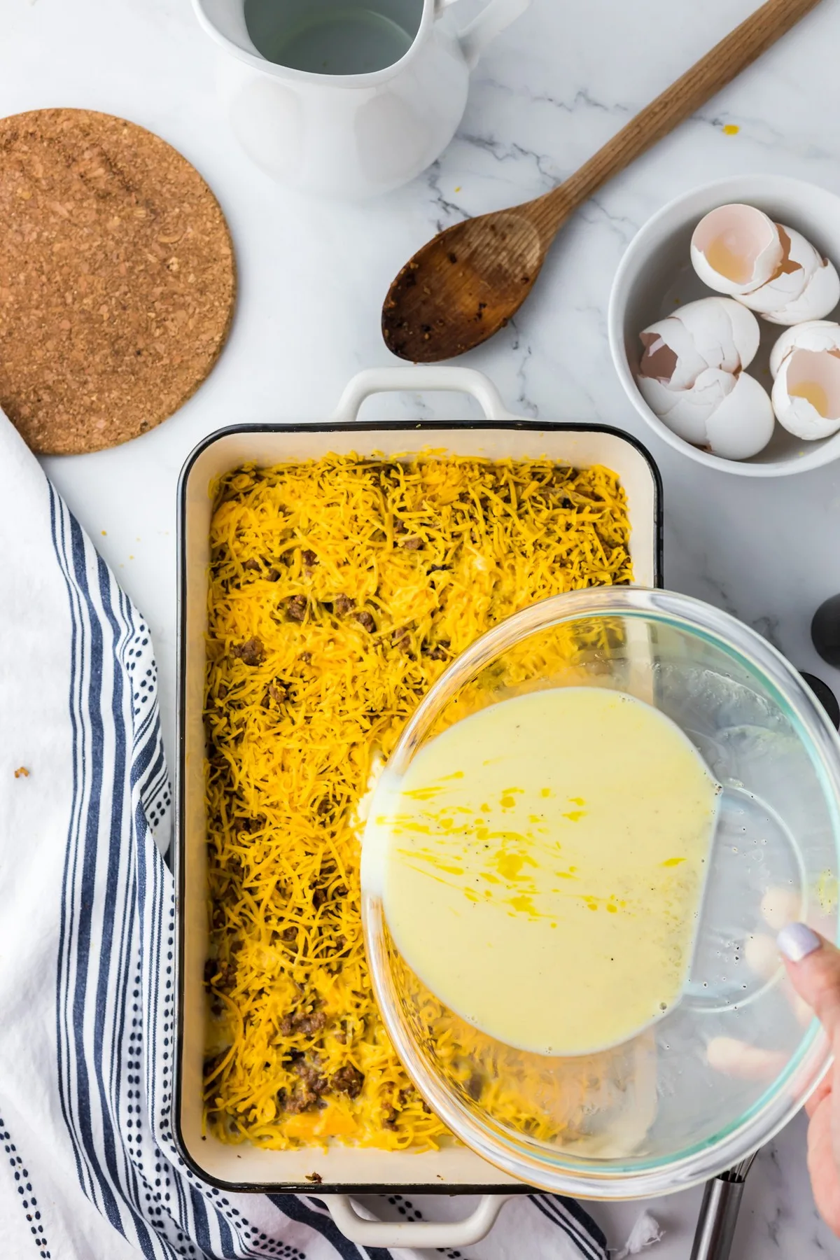 pouring milk and egg mixture over cheese