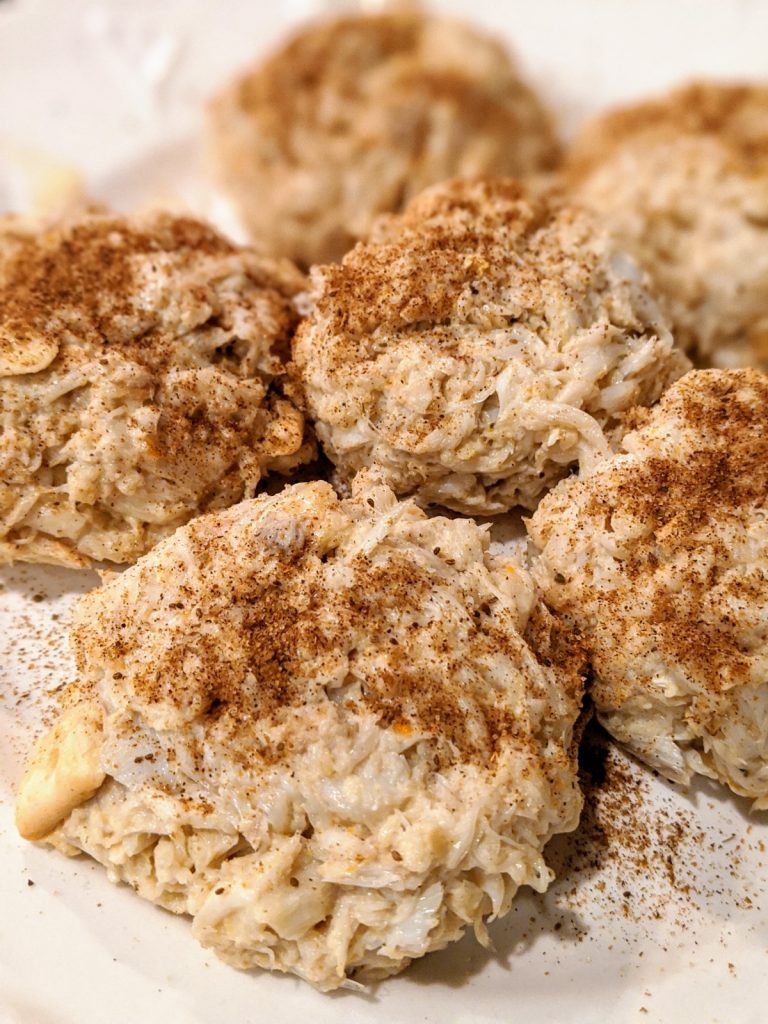 Uncooked crab cakes with old bay seasoning on top