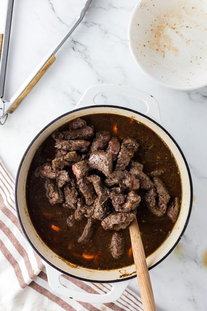adding beef to beef stew pot