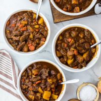 four bowls of beef stew with striped towel