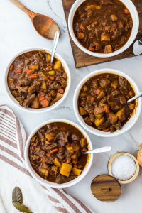 four bowls of beef stew with striped towel