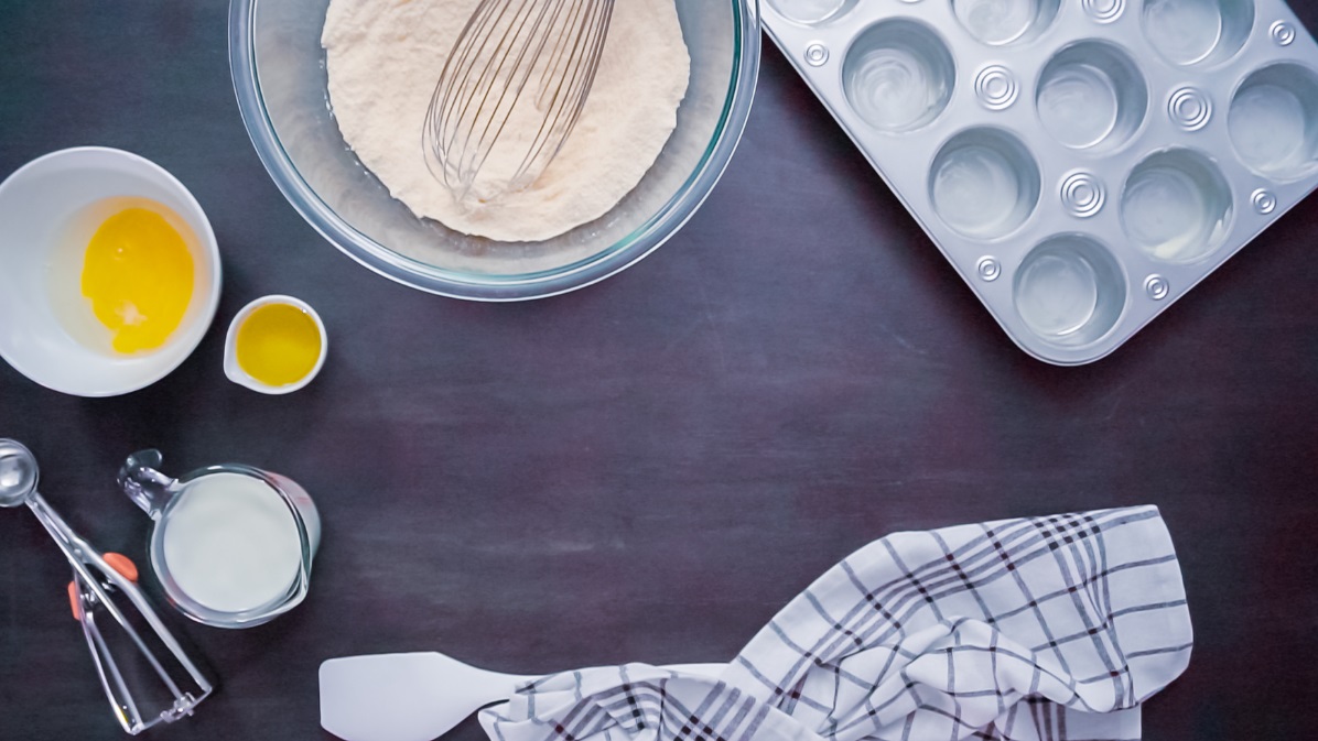 Ingredients of corn muffins laid out on dark backgroun