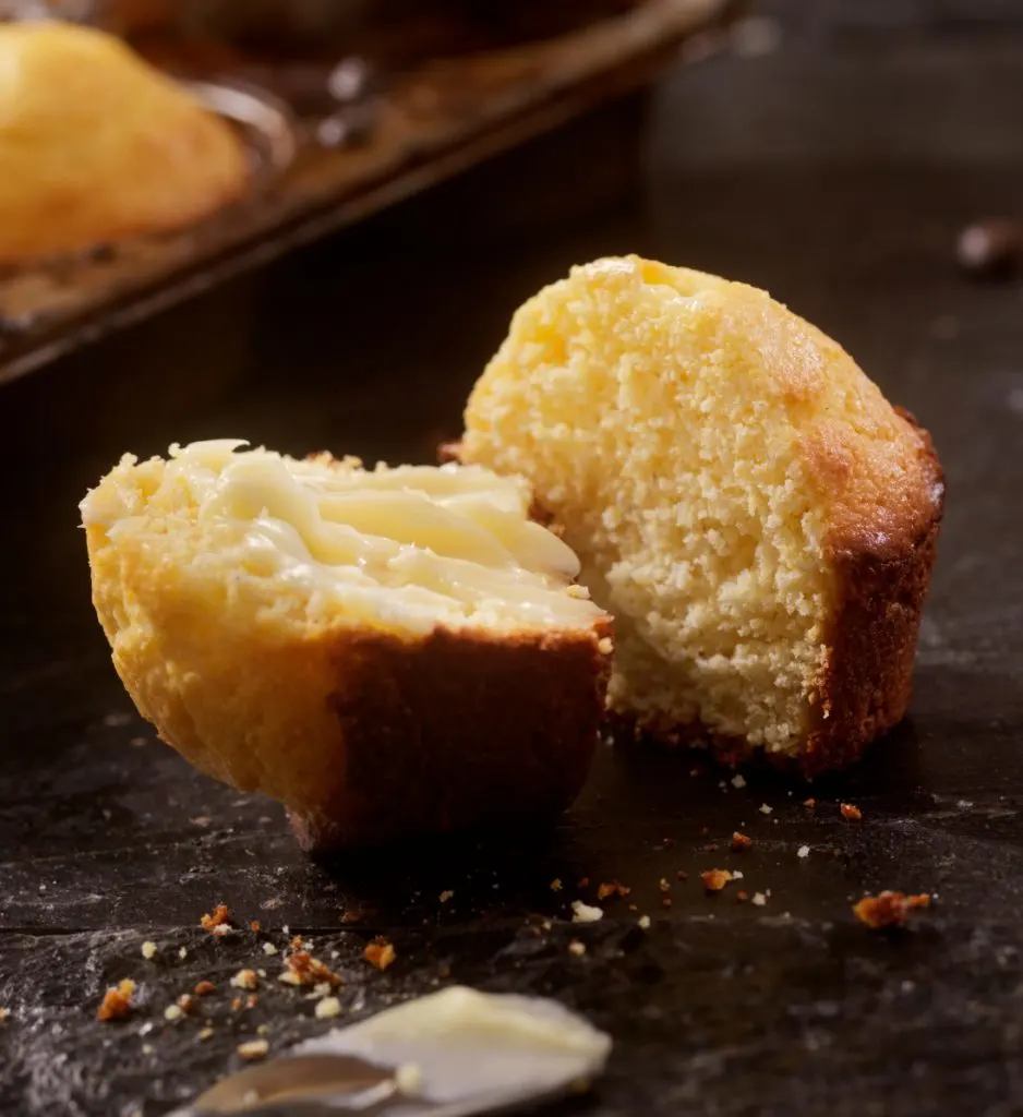 Corn muffin halved on dark background