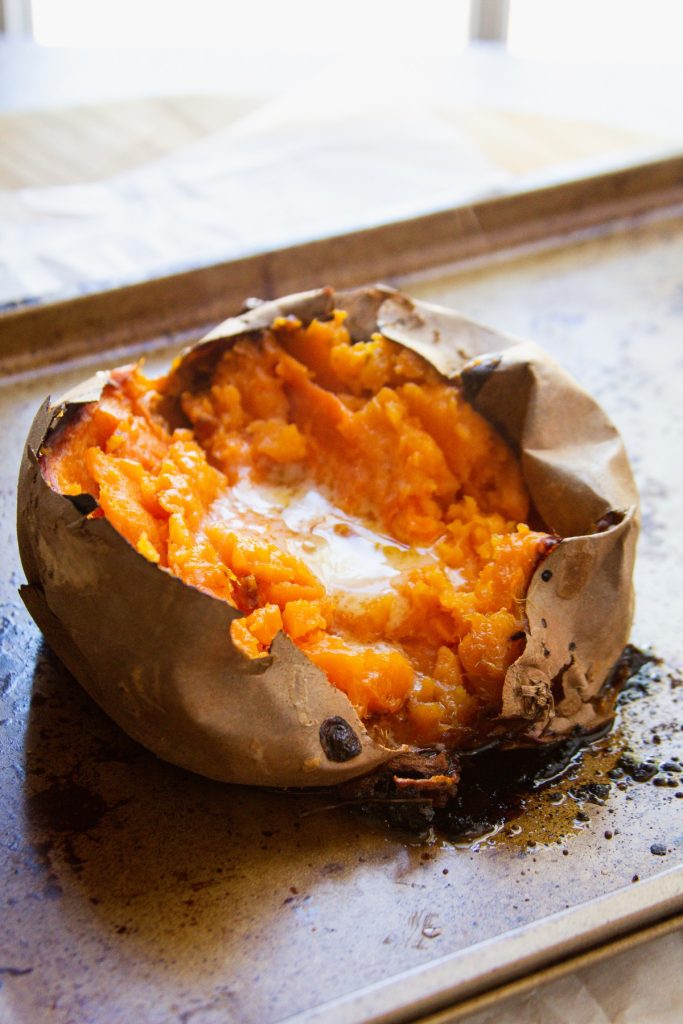 Split baked sweet potato on a pan with butter