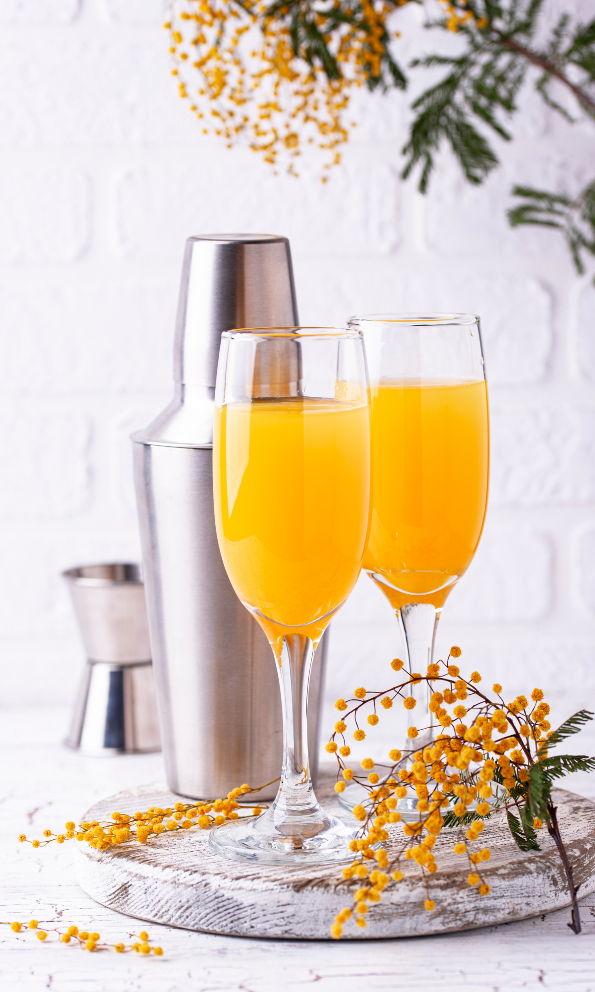 mimosa beverages in champagne flutes with shaker in background