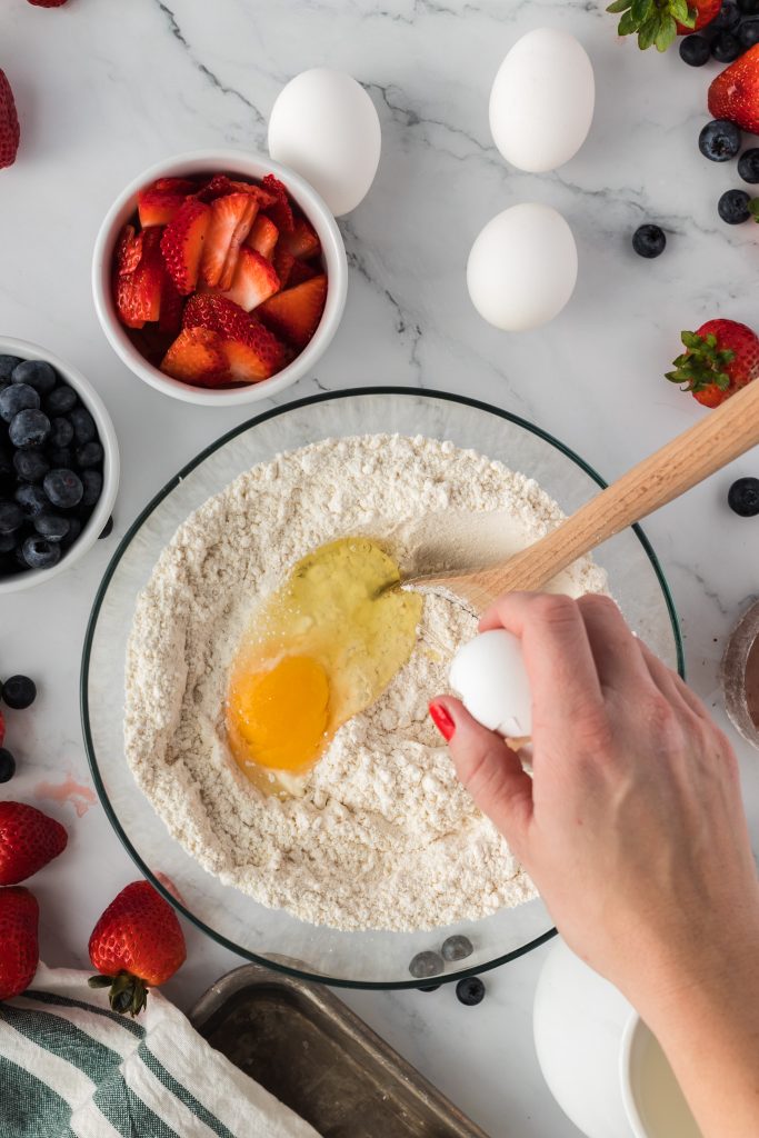 cracking egg into bowl of flour