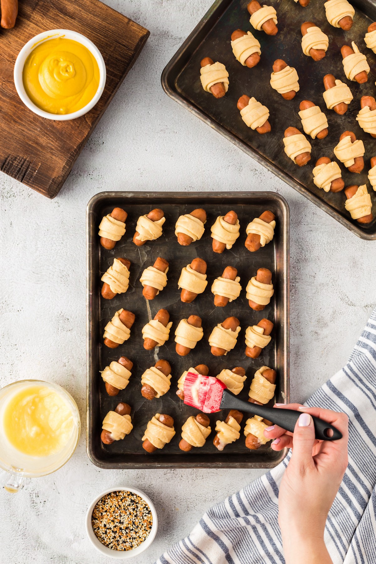 brushing on butter on pigs in a blanket