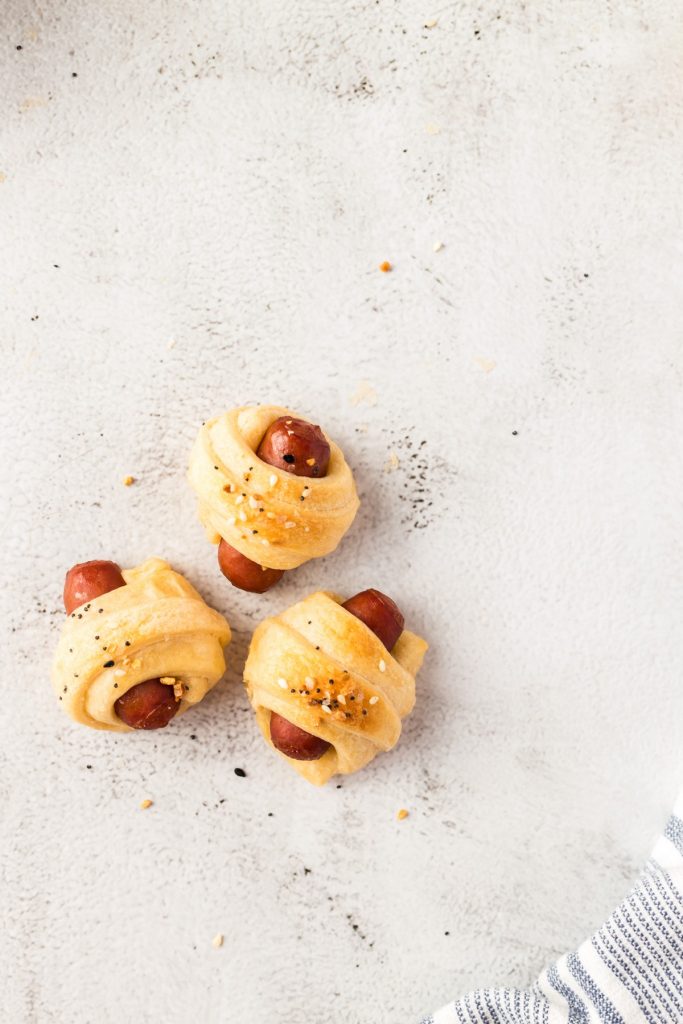 three pigs in a blanket on light colored background