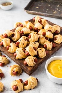 pigs in a blanket on cutting board with mustard