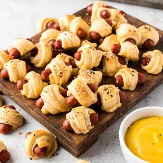 pigs in a blanket on cutting board with mustard