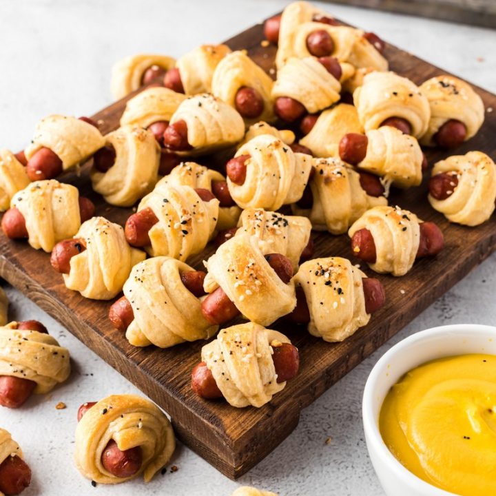 pigs in a blanket on cutting board with mustard