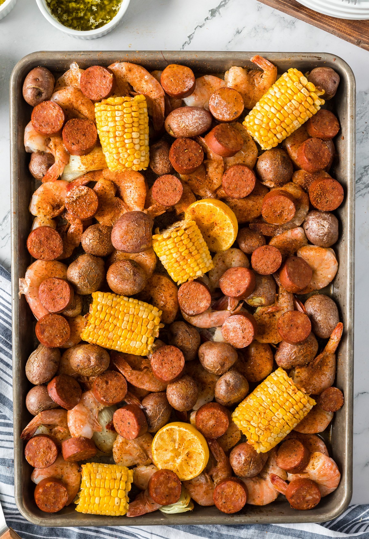 sheet pan of shrimp corn cobs sausage and potatoes.