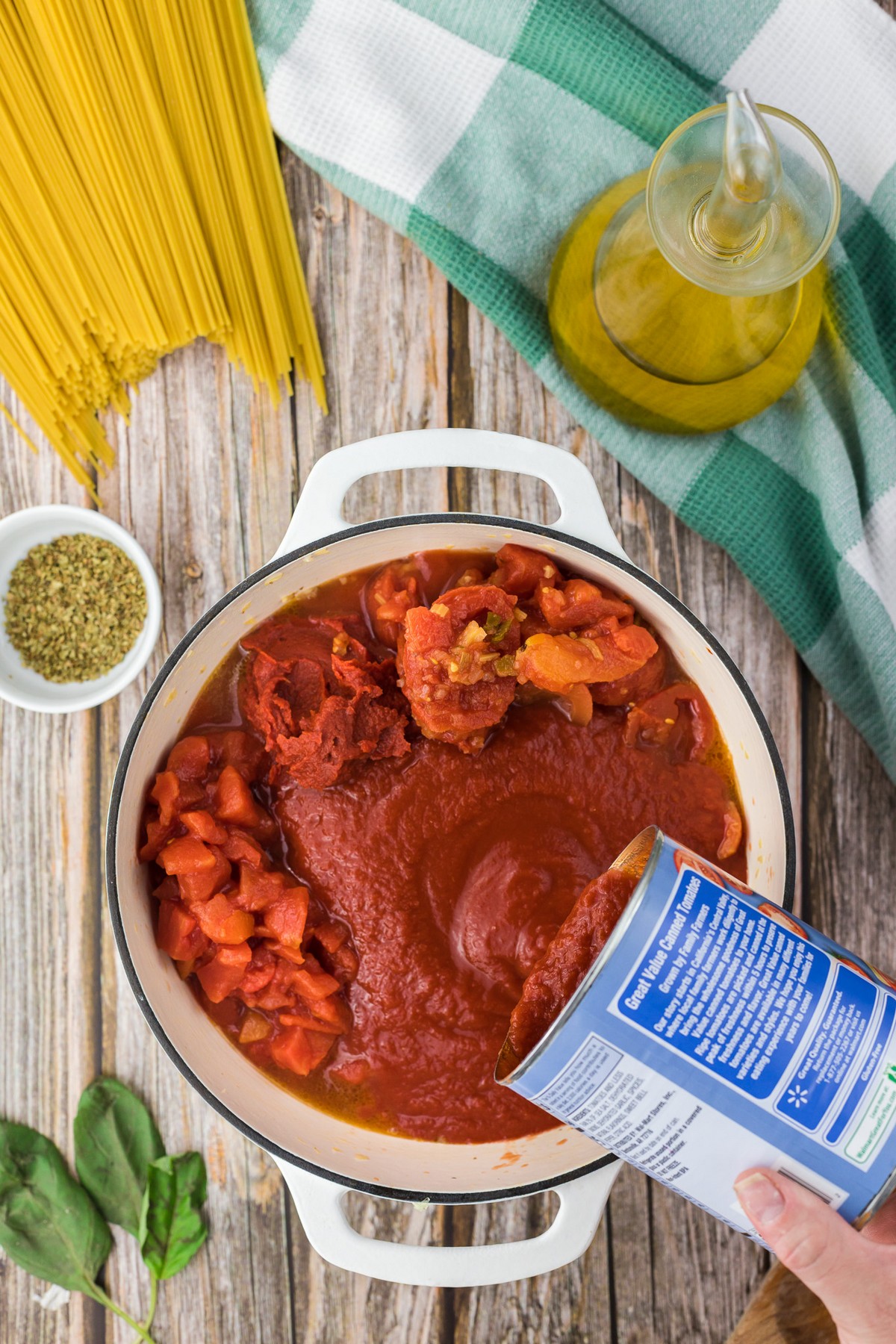 adding jar of red sauce to pot of spaghetti sauce