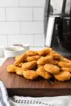 side shot of cooked chicken nuggets piled on cutting board