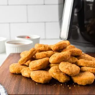 side shot of cooked chicken nuggets piled on cutting board
