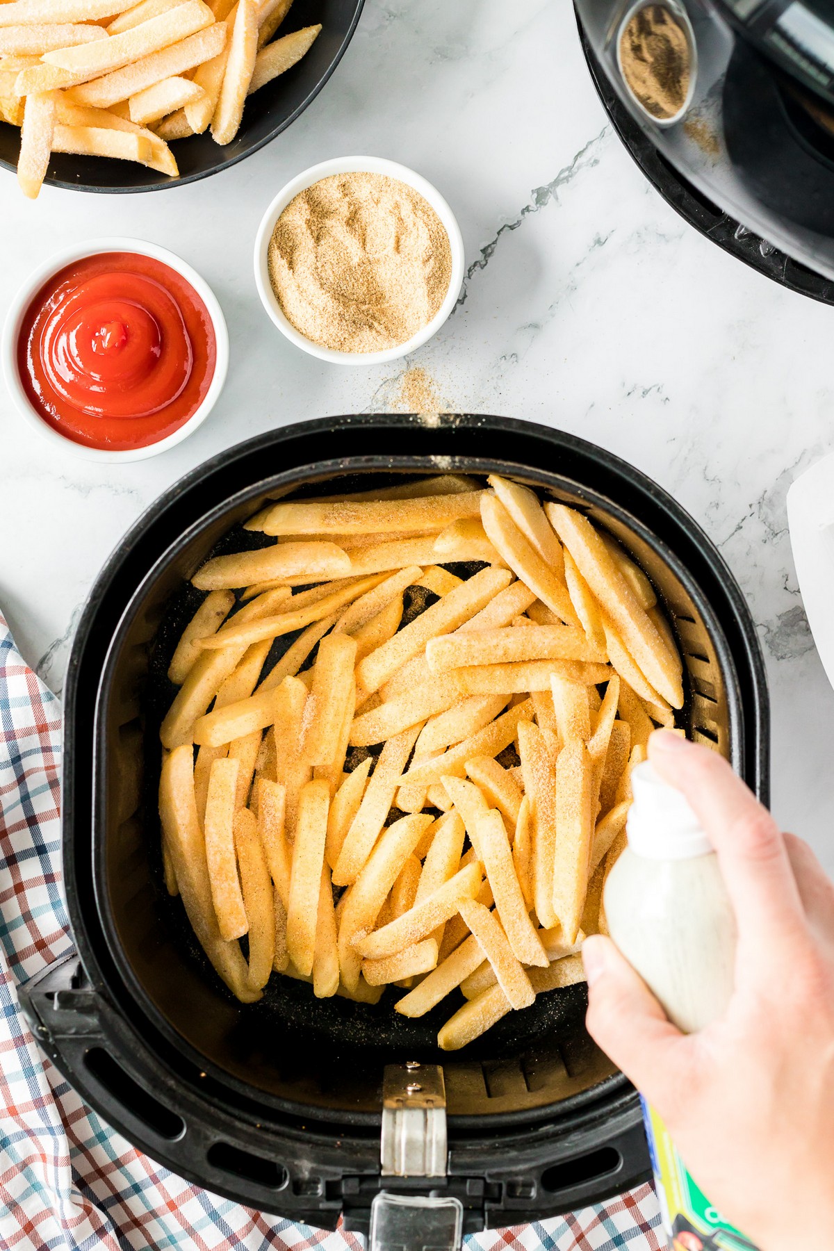 spraying oil on frozen french fries in air fryer