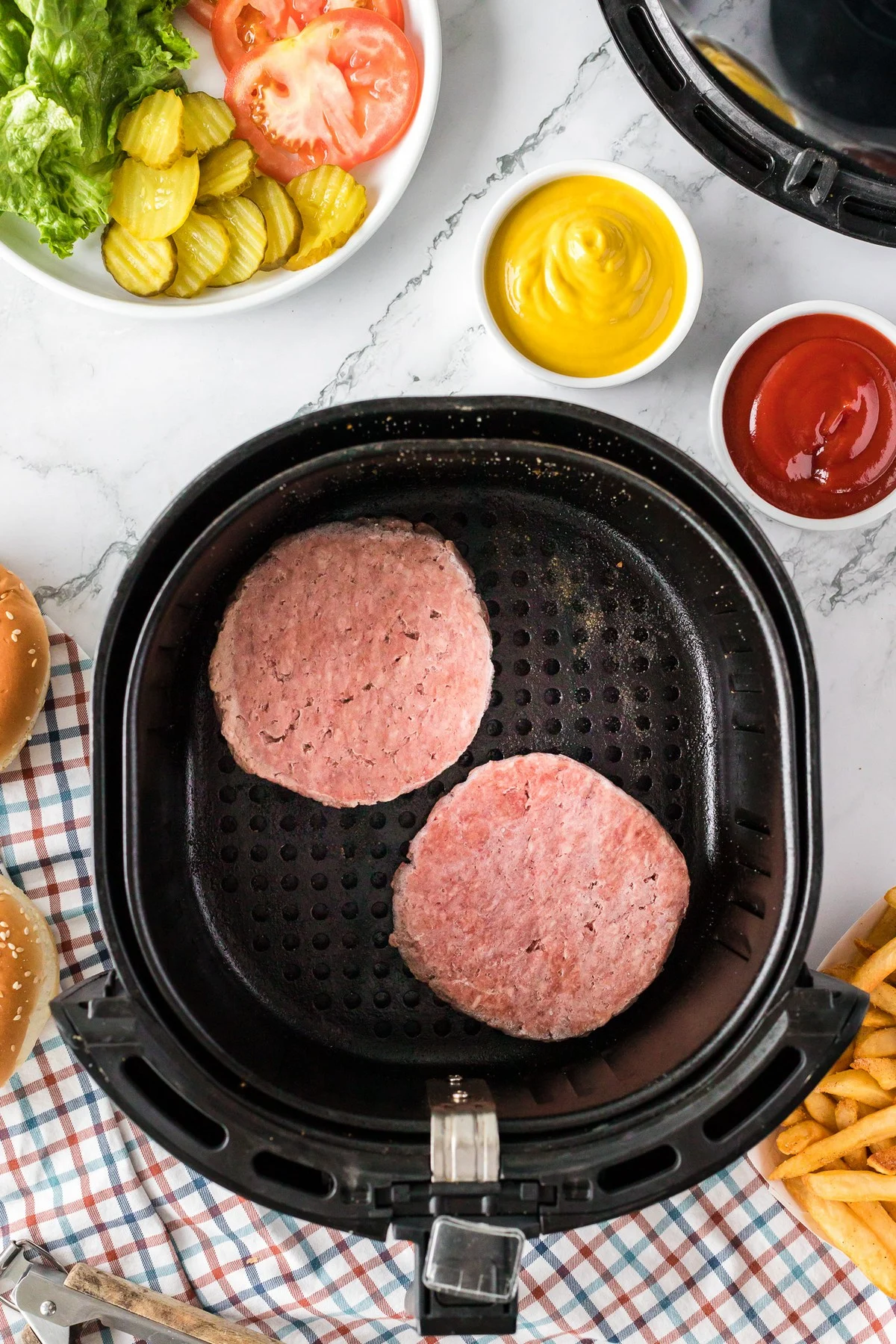 two frozen burger patties in the air fryer