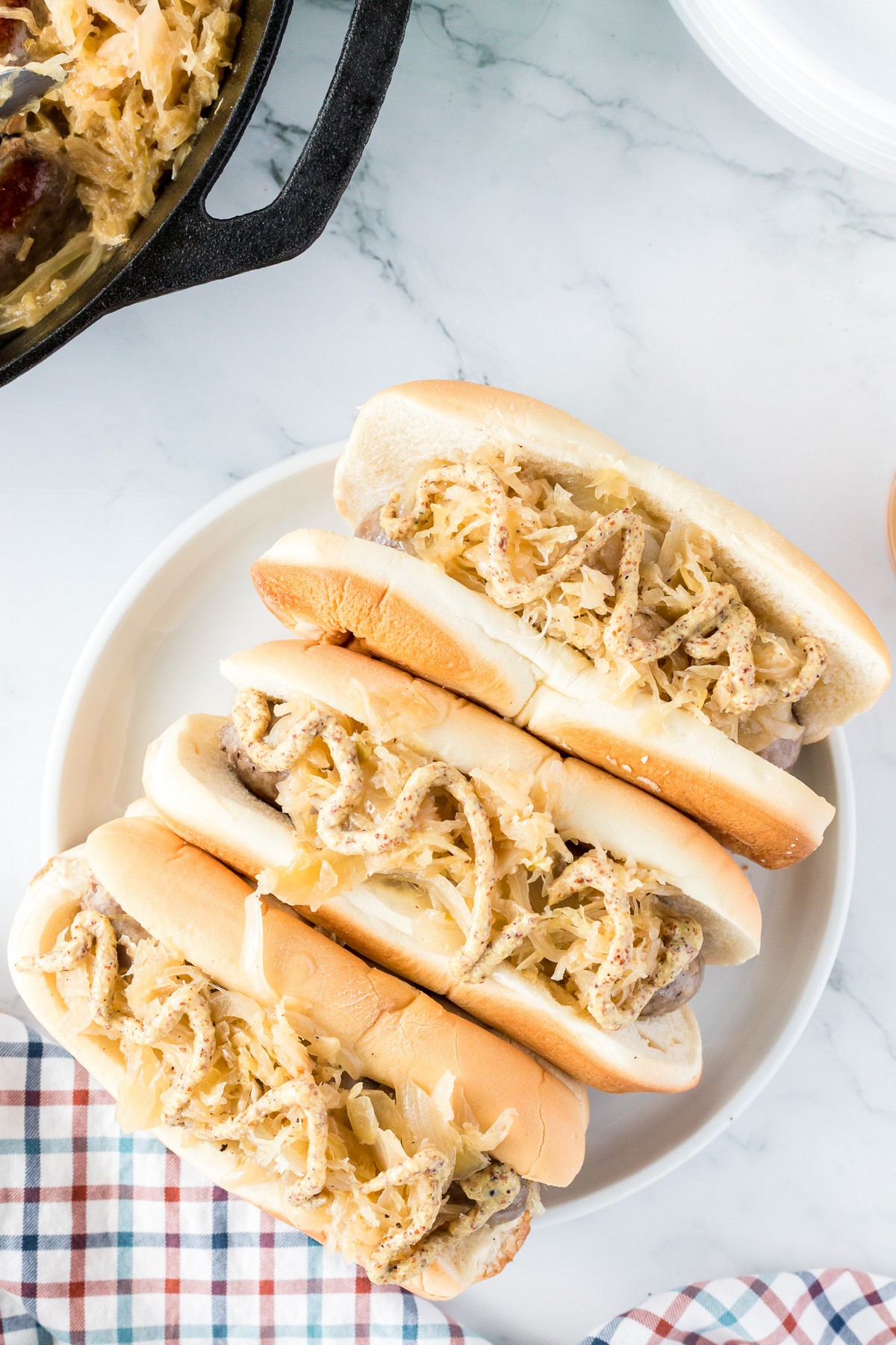 3 bratwursts in bun with sauerkraut and onions