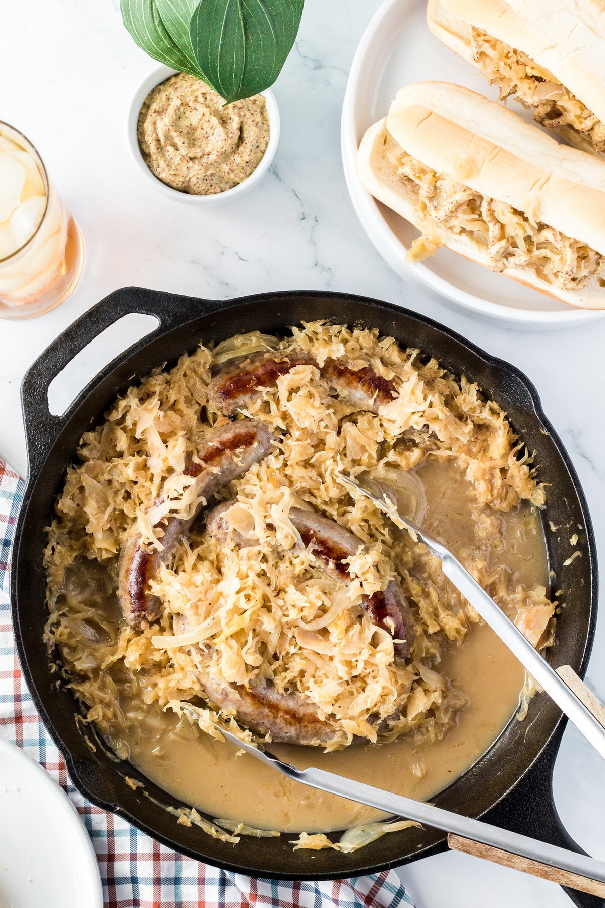 stirring skillet of bratwurst, sauerkraut and onions