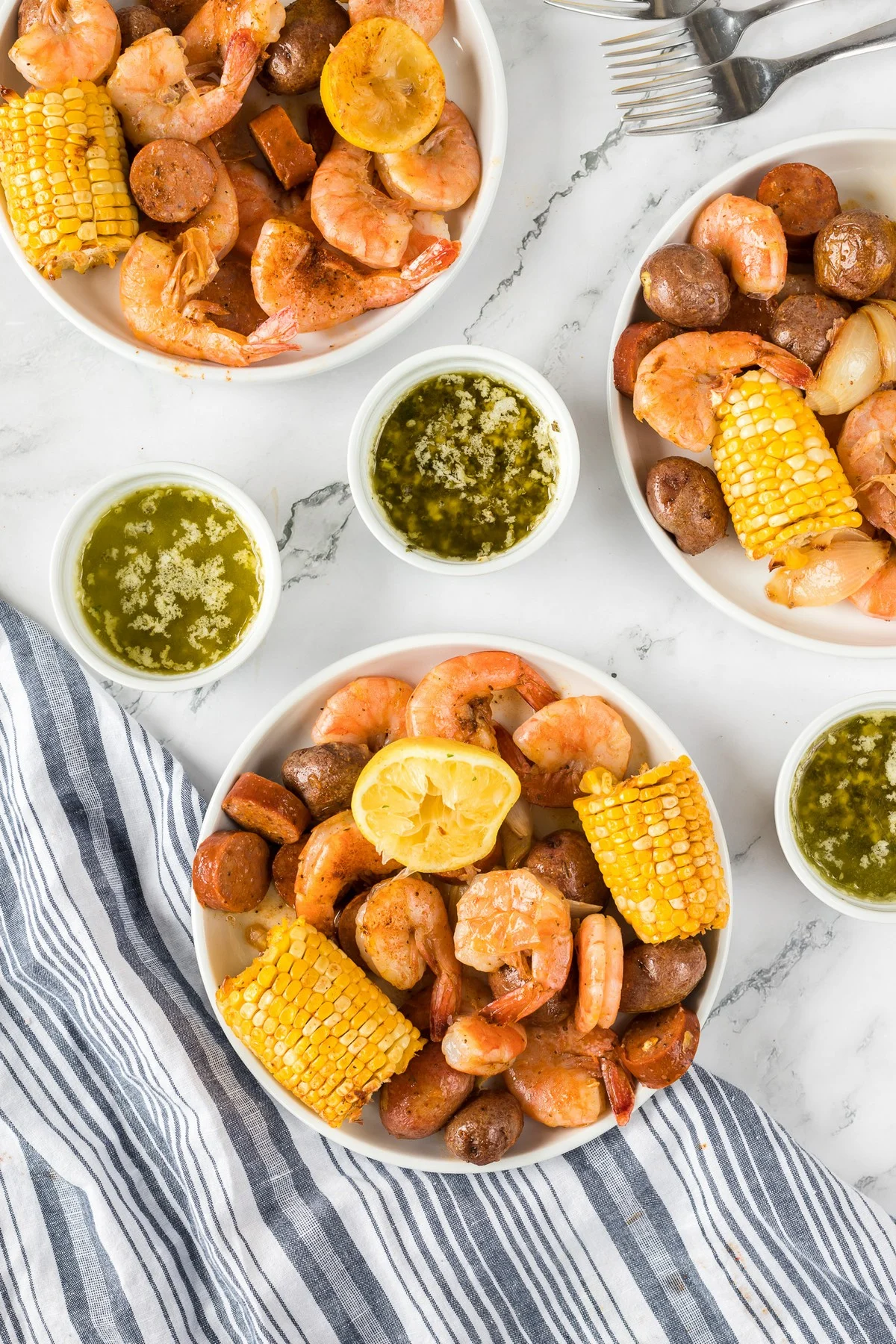 overhead image of bowls of seafood boil and ramekins of melted garlic butter