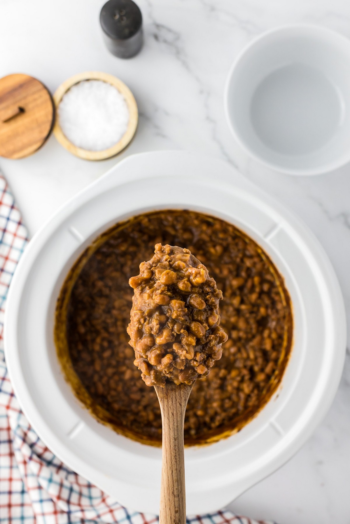 wooden spoon of baked beans with ground beef