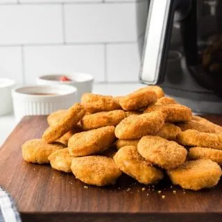 side shot of cooked chicken nuggets piled on cutting board