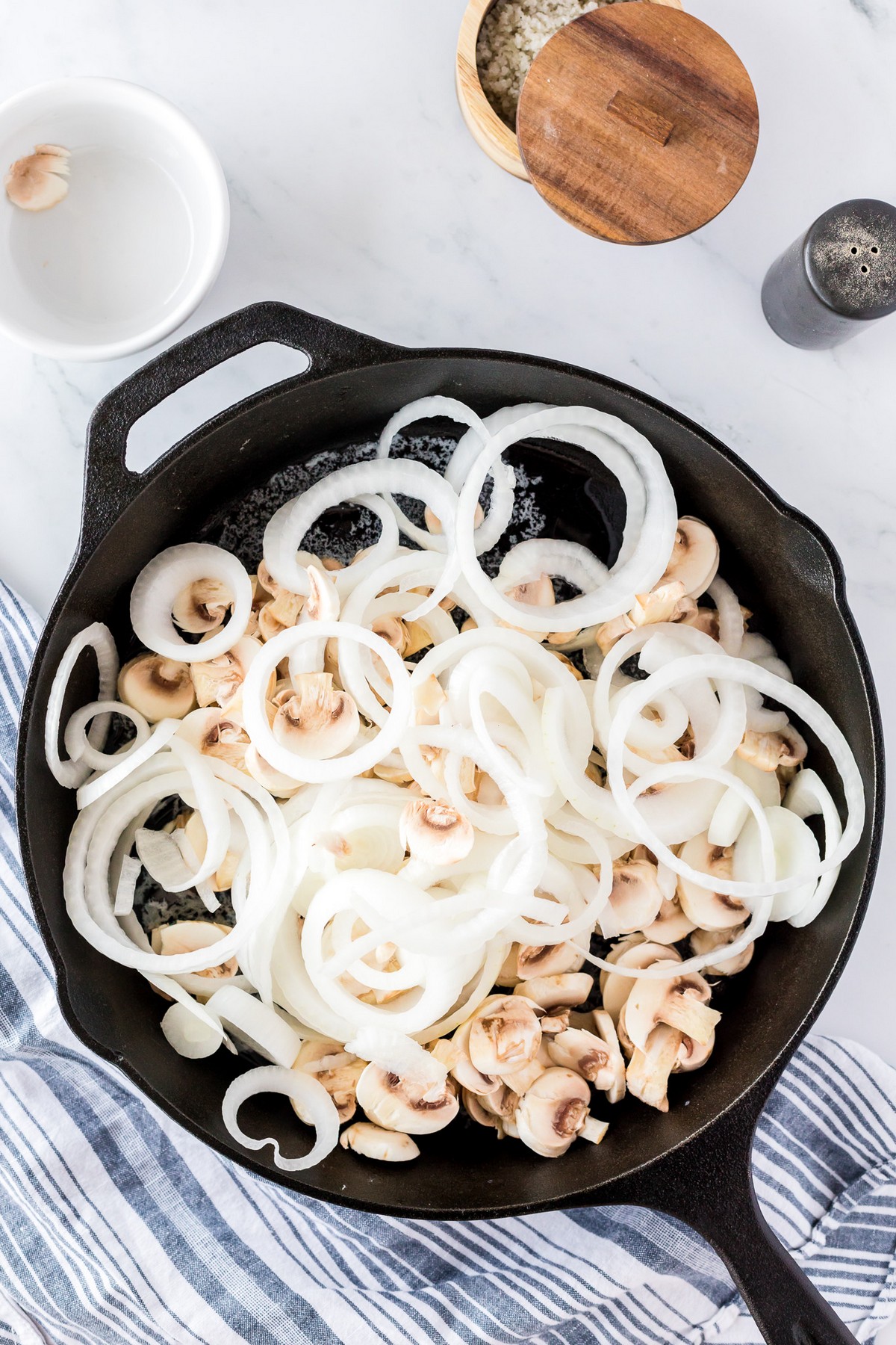 adding onions and mushrooms to a skillet