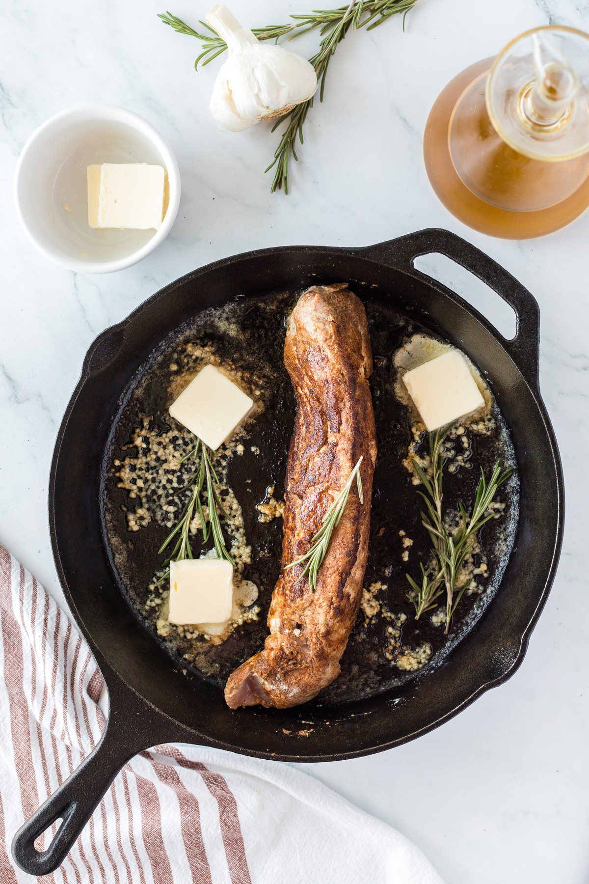 pork tenderloin with butter and rosemary in skillet