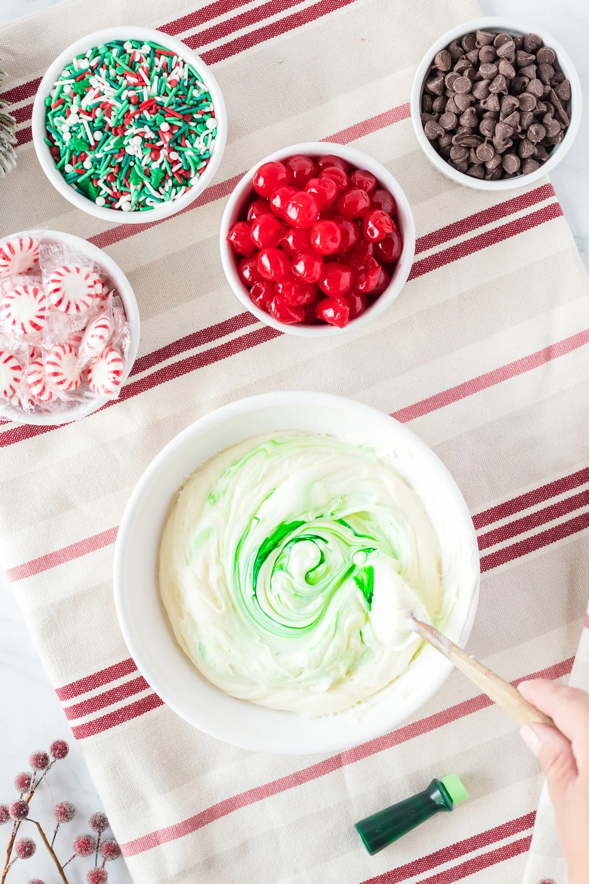 combining green food coloring and white icing in white bowl